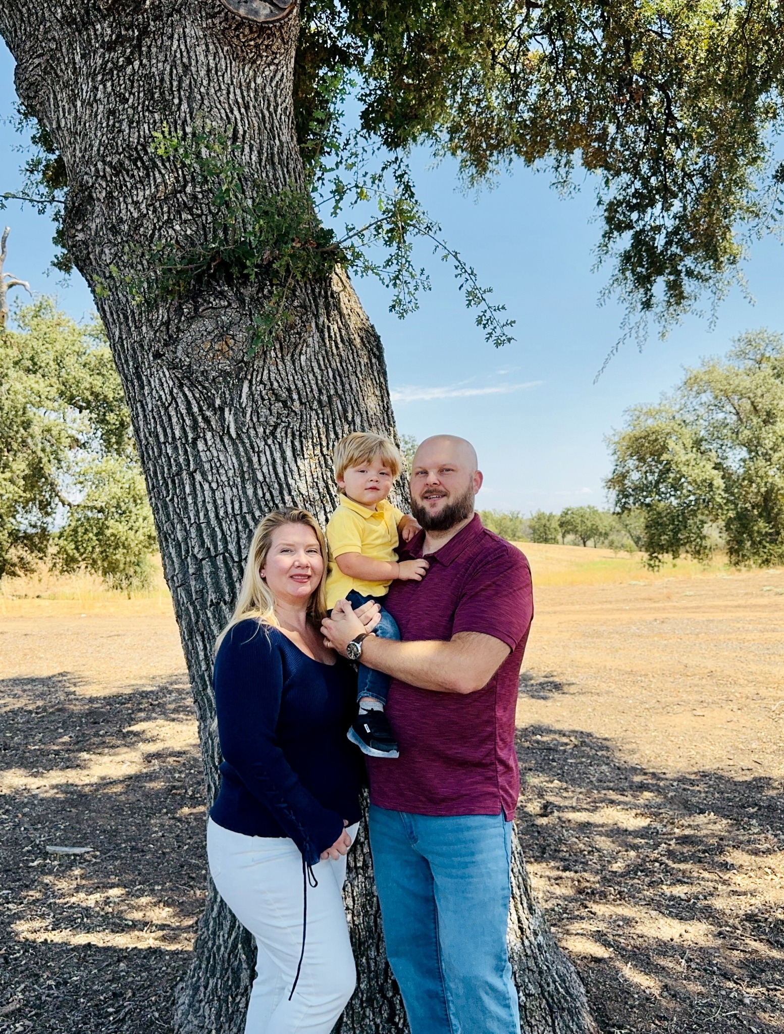 Christine with her husband and son beneath an oak tree in Lincoln
